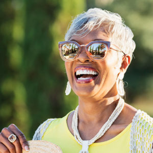 senior African-American woman in her 70s wearing sunglasses on a sunny day.
