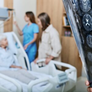 MRI of head of elderly woman in hands of doctor standing in medical ward near senior patient with relative and nurse. Recovery after a stroke